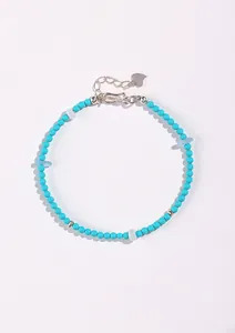 Close-up detail of the turquoise beaded necklace showing texture and silver heart charm