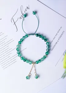 Detailed view of 6mm green natural moss agate beaded bracelet with gold dangle charm