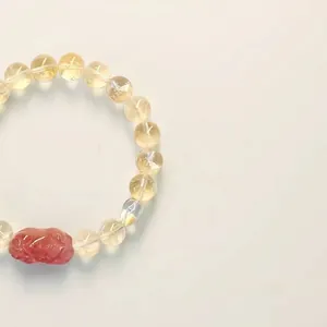 Gros plan de perles de citrine et d'une breloque Pixiu en quartz fraise