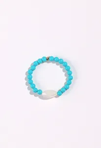 Detailed view of a handmade blue beaded bracelet with a central white oval gemstone