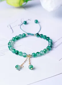 Close-up of green moss agate beaded bracelet featuring gold charms and adjustable green cord.