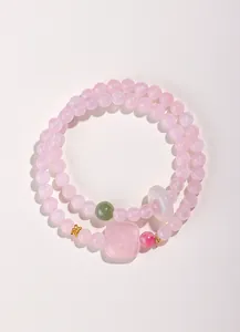 Gros plan d'un bracelet en perles de cristal rose avec divers pendentifs en pierre