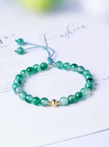 Macro view of 6mm natural moss agate beaded bracelet with gold accent bead
