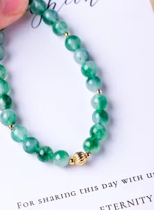 Macro detail of natural green moss agate beads on a 6mm minimalist bracelet with gold accents