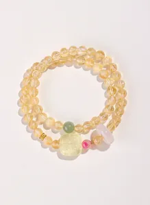 Gros plan détaillé des perles de citrine jaune naturel et du bracelet en jade vert sculpté