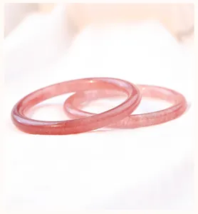 Detailopname van twee slanke aardbeikwarts armbanden op een zachte achtergrond