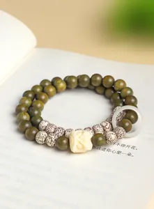 Detail van de dubbele groene sandelhouten kralenarmband met leeuwendans bedel