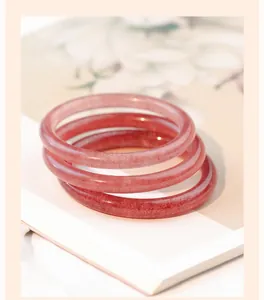 Detailopname van duivenbloedrode aardbeienkwarts armbanden op een florale tijdschriftachtergrond