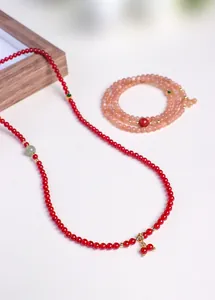 Detailweergave van de bordeauxrode granaat kralenketting en perzikkleurige kristallen armband