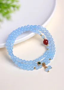 Detailopname van een meerlaagse lichtblauwe kristallen kralenarmband met rode granaat