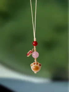 Gros plan détaillé d'un charm de sac patte de chat avec agate rose et étiquette dorée