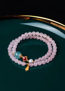 Vue détaillée d'un bracelet en quartz rose à deux rangs avec breloque hulu dorée