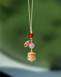 Gros plan détaillé sur la perle Bodhi Maneki-neko et l'agate rose de ce joli pendentif