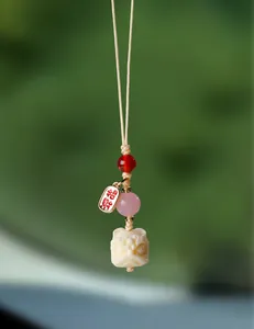 Détail d'un pendentif lion sculpté avec des perles d'agate rose sur un cordon beige