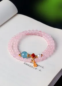 Vue rapprochée d'un bracelet en cristal rose avec un pendentif doré et une perle bleue.