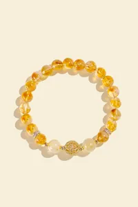 Detailed view of a golden rutilated quartz crystal bracelet with ornate gold beads