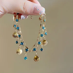 Detailopname van een dubbellaagse gouden ketting met blauwe strassteentjes en schelpen