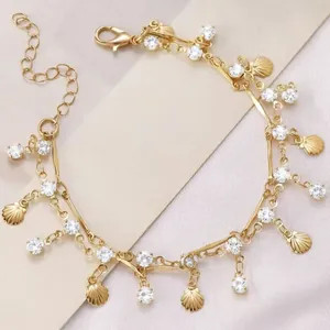 Detailopname van een elegante gouden gelaagde ketting met schelphangers en kristallen