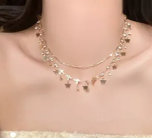 Detail van een goudkleurige dubbellaagse ketting met sterhangers op de nek.
