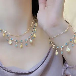 Gedetailleerd overzicht van gouden schelphanger ketting en armband set met blauwe stenen
