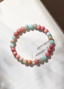 Detailaufnahme eines pastellfarbenen Natursteinarmbands aus Rhodonit und Achat