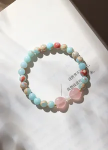 Detailaufnahme eines Naturrosa Quarz Herz und blauen Stein Perlenarmbands in sanftem Licht