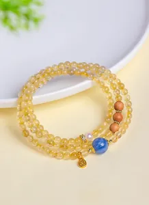 Vista detallada de una pulsera de cuarzo rutilado dorado natural con una piedra azul.