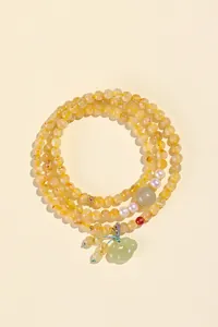 Detalle de un collar de cuentas de cuarzo rutilado amarillo con perla y jade
