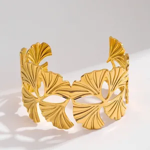 Dettaglio del motivo a foglie di ginkgo su un bracciale rigido in acciaio dorato
