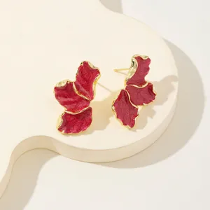 Vista dettagliata di eleganti orecchini a petalo rosso smaltato con bordi dorati lavorati