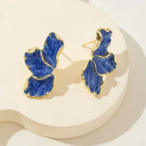 Primo piano dettagliato di orecchini a foglia blu con eleganti bordi dorati fini