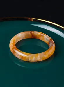 Primo piano di un bracciale in cristallo giallo naturale con venature ambrate uniche.