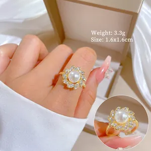 Dettaglio di un elegante anello d'oro con perla e fiore di zirconi scintillanti