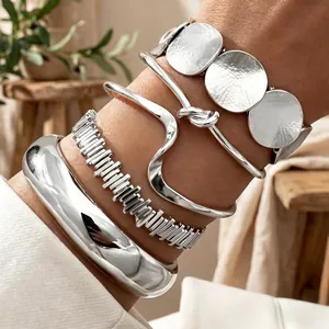 Dettaglio di bracciali in metallo argento a strati con design lisci, ondulati e martellati