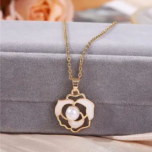 Dettaglio di un ciondolo per collana a forma di camelia dorata con perla centrale