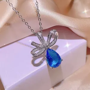 Dettaglio ravvicinato di un'elegante collana a fiocco con una gemma blu a goccia d'acqua.