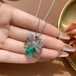 Dettaglio di una collana con ciondolo a fiocco e una pietra verde smeraldo