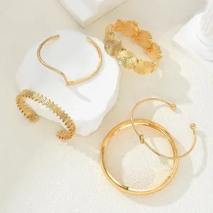 Detailed macro shot of various trendy gold-plated metal bracelets and cuffs for women.