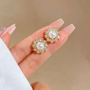 Dettaglio di orecchini a fiore con perle e petali di strass su base dorata elegante