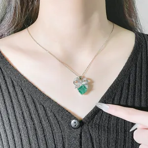 Dettaglio di una collana elegante con gemma verde e pendente a fiocco scintillante