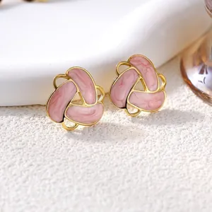 Dettaglio ravvicinato di orecchini vintage in smalto rosa con fiori geometrici dorati