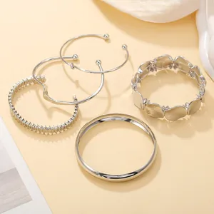 Detailed view of a five-piece set of silver-tone metal bracelets in various designs.