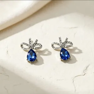 Primo piano dettagliato di orecchini a fiocco in argento con pietre blu scuro