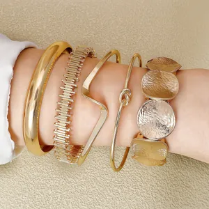 Detailed view of five-piece gold metal multi-layer bracelet set with hammered textures