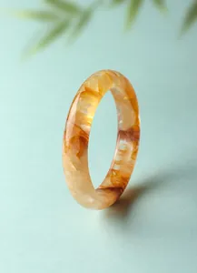 Dettaglio di un bracciale in quarzo fantasma giallo naturale su sfondo blu chiaro
