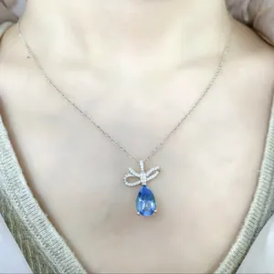 Dettaglio di una collana a goccia blu con pendente a fiocco in cristallo sul collo.