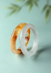 Primo piano di bracciali in cristallo fantasma bianco e giallo su sfondo verde tenue