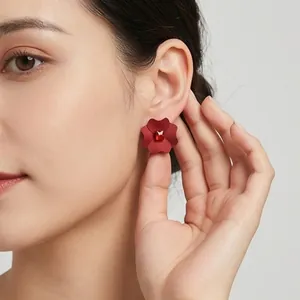 Dettaglio di un orecchino a perno a forma di fiore rosso con uno strass centrale