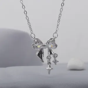 Close-up of silver bow necklace with heart-shaped zirconia and star pendant.