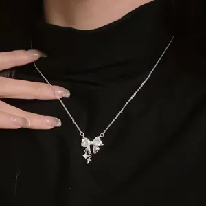 Close-up of elegant silver bowknot pendant necklace on a black turtleneck dress.